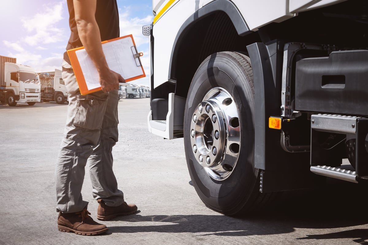 Truck driver checking truck tires during maintenance inspection